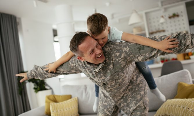 Soldier having fun with his son at home. Father and son playing in living room.